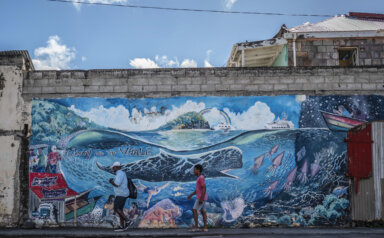 People walk past a mural of a whale created by artist Marcus Cuffi in Roseau, Dominica, Sunday, Nov. 12, 2023.