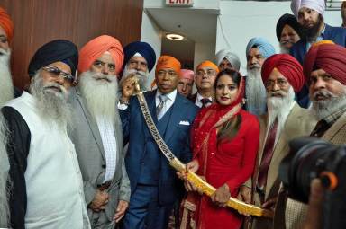 Assemblywoman Jenifer Rajkumar presents a kirpan to Mayor Eric Adams with members of the Sikh community looking on.