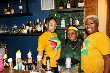 Proudly representing the Guyana flag, staff of BleuFin Bar & Grill joins proprietor, Hollis Barclay, right, who opened the eatery at 637 Nostrand Ave., Brooklyn in 2019, just before the coronavirus pandemic decimated small businesses.