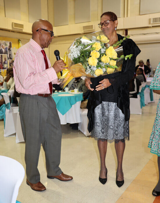 Pastor Robert McBarnett presents bouquet of flowers to Vaughan Toney's widow, Bridget.