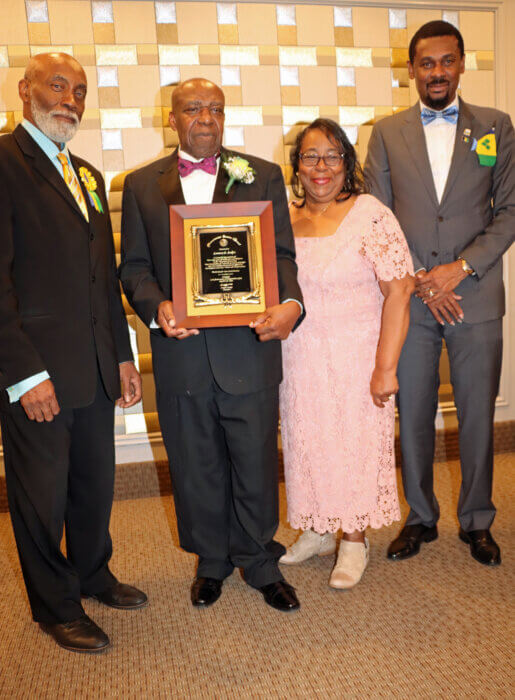 Lennox Joslyn receives an award from COSAGO President Crispin Friday, left, flanked by his wife, Ava, and Consul General Rondy "Luta" McIntosh.