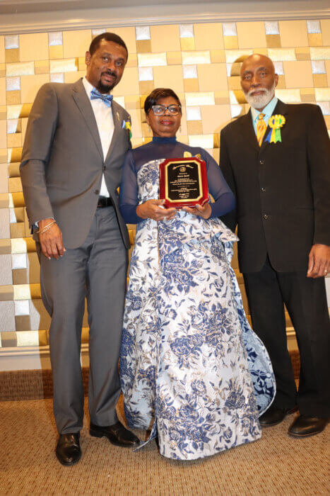 Laverne McDowald-Thompson, COSAGO vice president, receives award, on behalf of veteran Vincentian broadcaster Donn Bobb, flanked by COSAGO President Crispin Friday, right, and SVG Consul General Rondy "Luta" McIntosh, left.