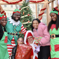 Dale Charles, AKA Mrs. Clause is joined by her elves, and starry-eyed community kids after receiving gifts at the Bed-Stuy Winter Wonderland Christmas at the intersection of Fulton Street and Marcy Avenue.