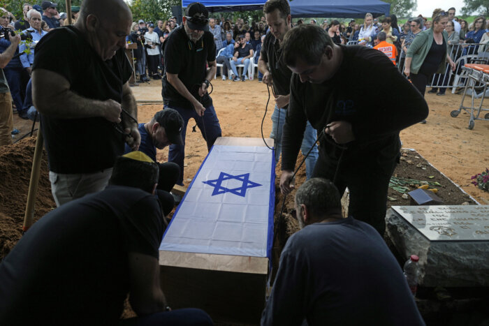 The coffin containing the remains of Alon Shamriz, 26, is lowered to his grave during his funeral in the cemetery of Kibbutz Shefayim, southern Israel, Sunday Dec. 17, 2023. Shamriz was one of three hostages mistakenly shot to death by Israeli troops Friday in a battle-torn neighborhood of Gaza City.