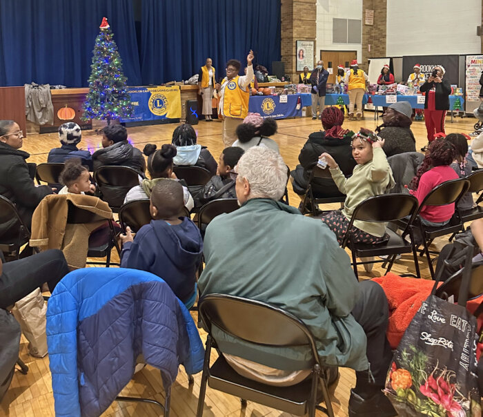 Brooklyn Canarsie Lions Club President Jean Joseph, left hand raised, gives welcome remarks.