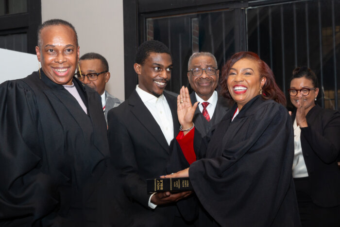 Justice Sharon Bourne-Clarke being sworn in by Justice Wavny Toussaint, presiding Justice Appellate Term Supreme Court 9th 11th and 13th Judicial District; Justice Bourne-Clarke's father in background. Her son, Brandon, is holding the Bible.