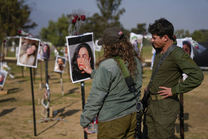 Israeli soldiers look at photos of people killed and taken captive by Hamas militants during their violent rampage through the Nova music festival in southern Israel, which are displayed at the site of the event, to commemorate the October 7, massacre, near kibbutz Re'im, Friday, Dec. 1, 2023.