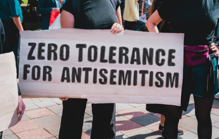 The phrase " Zero tolerance for antisemitism " drawn on a carton banner in hand.