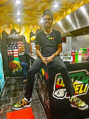 Joshua Dat sitting on top of the counter inside his restaurant, Datz Deli.