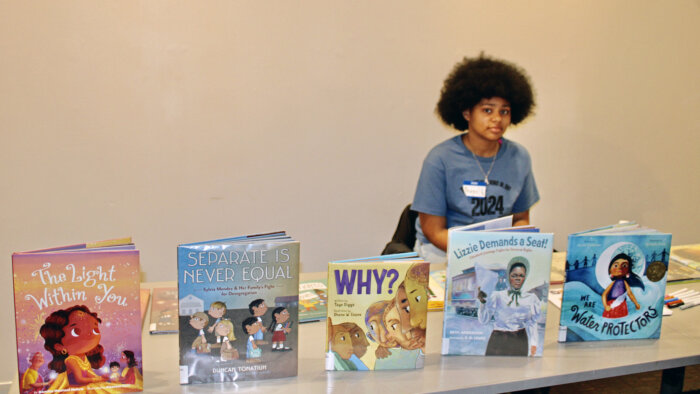 Eighth grader Avigail Herdondon, shares books from the Brooklyn Public Library, Macon Branch, during a MLK Call to Action expo at the Weeksville Heritage Center in Crown Heights.