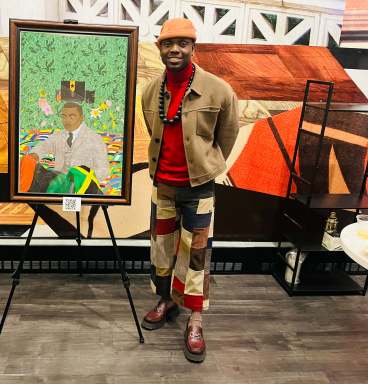 Watson Mere stands in front of a painting of Marcus Garvey entitled "The Complicated Crown,” which represents the complexity of Garvey's legacy.