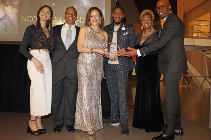 Nicole Hollant-Denis, third from left with award, flanked by family members, to her right; Public Advocate Jumaane Williams, fourth from left; Rose Guerrier, fifth from left; and Jacques M. Leandre, right.