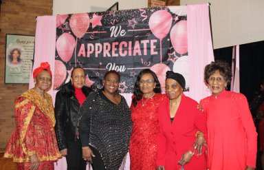 A group of elegantly dressed older adults against a backdrop that says we appreciate you at the 2nd Annual Valentine's dinner in the auditorium of Holy Family Church in Canarsie, Brooklyn.