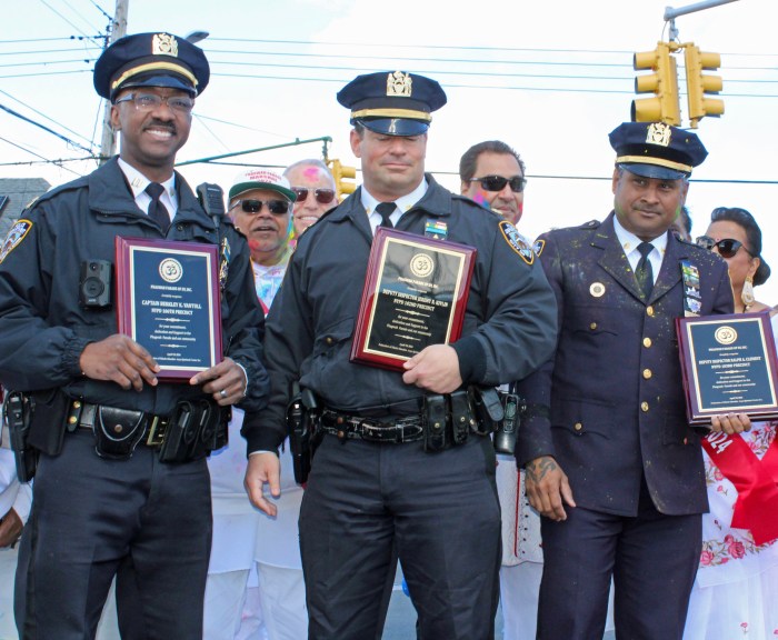 NYPD Officers Berkley VanTull, captain, commanding officer of the 16 Precinct, Jeremey R. Kelvin, deputy inspector of the 102 Precinct, and Deputy Inspector, Commanding Officer Ralph A. Clement, in that order, display plaques from the Phagwah Committee for their commitment to the celebration, during the 36th Annual Phagwah parade in Little Guyana, Queens last Sunday.