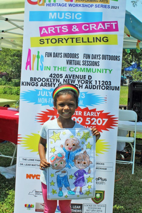 A summer series camper shows off her artwork at a previous Summer Series Workshop in Canarsie Park, Brooklyn as part of the Guyana Folk Festival calendar of events.