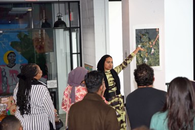 Raqeeba Zaman showcasing artwork during a walking tour at Oyate Group's "Indian Arrival: Indentured Survival" art exhibition.