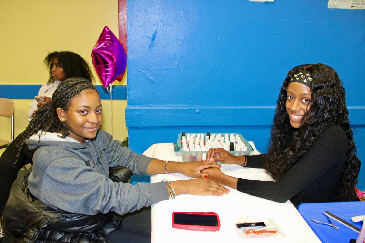 A young lady receiving a manicure treatment, compliments of Abryana Henry owner of "A Marie Make-up Artistry", during Sen. Kevin Parker's 15th Annual Prom Dress giveaway, at Samuel J. Tilden Educational Campus.