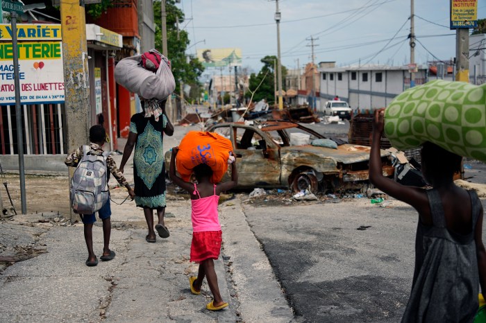 Residents walk past road blocks as they evacuate the Delmas 22 neighborhood to escape gang violence in Port-au-Prince, Haiti, Thursday, May 2, 2024.