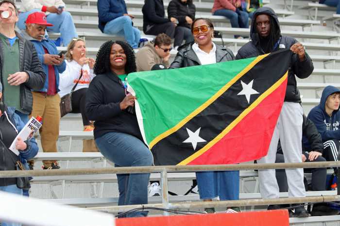 Kylla Herbert, left, and other nationals display the St. Kitts and Nevis flag at the Penn Relays.