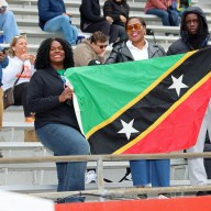 Kylla Herbert, left, and other nationals display the St. Kitts and Nevis flag at the Penn Relays.