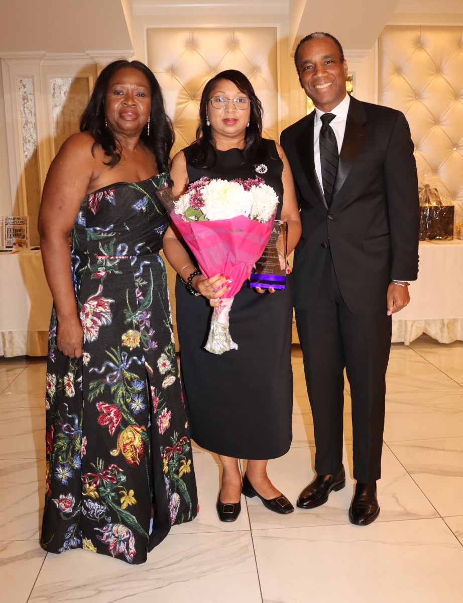 Michelle Stoddart, center, receives award and bouquet of flowers from Justice Sylvia Hinds-Radix and Rudyard Whyte, Esq.