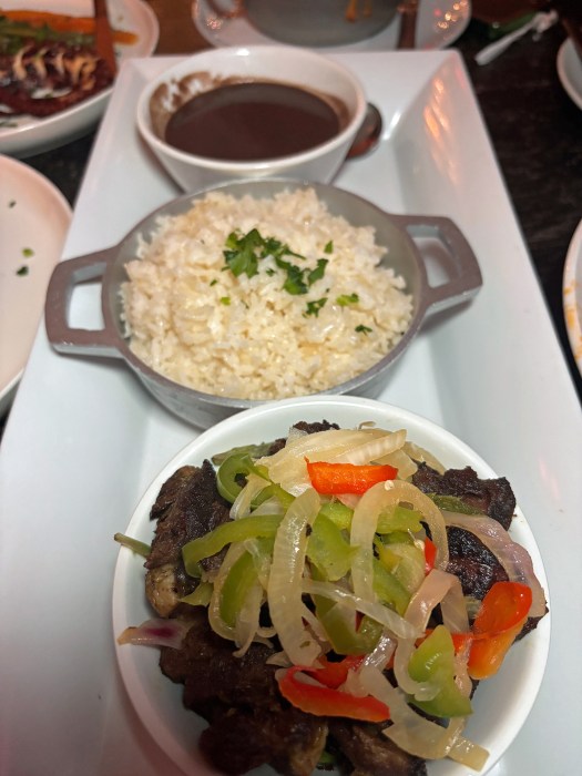 A flavorful plate of rice, vegetables, and griot, a Haitian classic, is served at Djon Djon Restaurant.