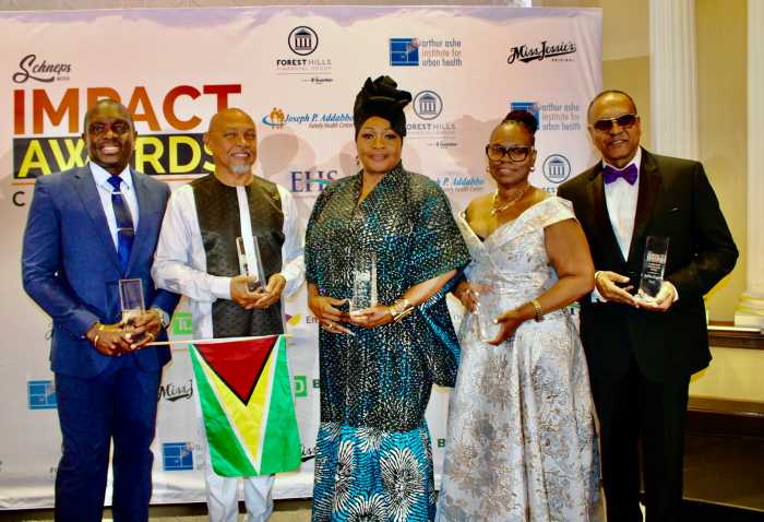 The exceptional contributions made by Guyanese nationals were acknowledged at the Annual Caribbean Life Impact Awards, on March 20, at Terrace on the Park in Queens. From left, JetBlue pilot Haslyn Anson Peters, Advocate Antoine B. Craigwell, owner of The Hills Restaurant in Brooklyn, Doris Rodney, Dr. Rhonda E. Phillips, and Rowtas ‘Roger” Sing, with their crystal awards. Captain Peters proudly displays his nation's Golden Arrowhead of Achievement flag.