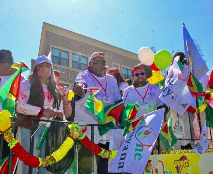 Consul General of Guyana to New York, Michael E. Brotherson, second from left, extends a flag to celebrants from a One Guyana float at the 37th Phagwah Parade in Richmond Hill Queens. Businessman Dave Narine at CG's left, was part of the float that included Ambassador to Washington Samuel Hinds, and Head of the Diaspora Unit, Joseph Yussuff.