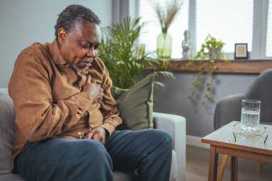 Lonely grandfather suffering from heart disease at home, feeling pain, and alone.
