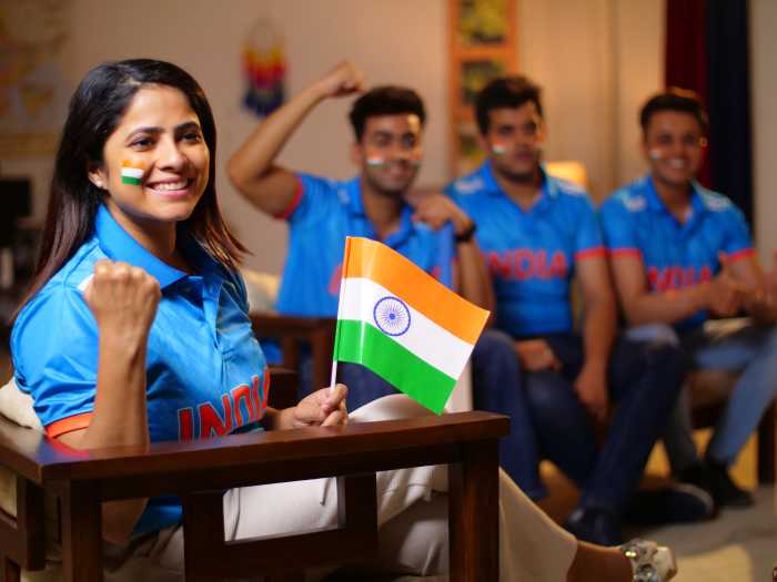 Excited cricket fans sitting at home watching a game on TV.