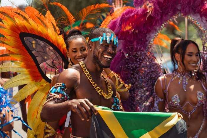 A masquerader proudly displays a Jamaican flag at the 2025 Carnival in Kingston, Jamaica.