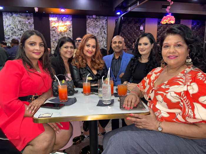 Rondel Boodram, owner of Sandz NY surrounded by guests as they enjoy the vibrant ambiance of Sandz NYC’s soft opening, featuring live music and Caribbean-inspired décor.