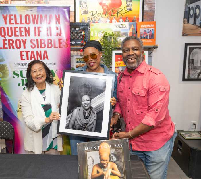 Miss Pat of VP Records (left) and photographer Ajamu Myrie present a portrait of Queen Ifrica to the singer.