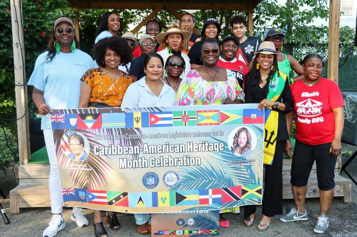 Caribbean-American legislators with staff and volunteers display banner.