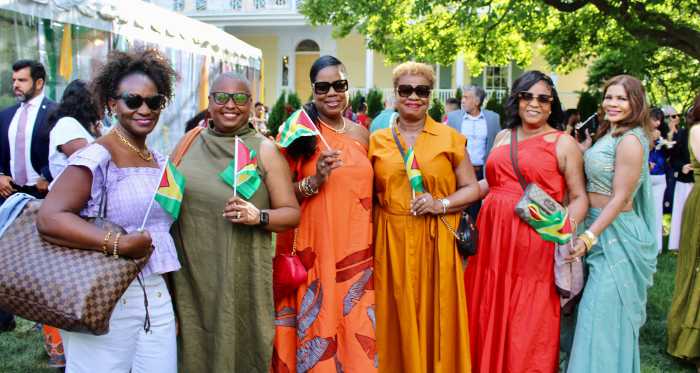 A colorfully dressed bevy of beautiful ladies proudly show their Golden Arrowhead flag of freedom on the lawn of Gracie Mansion in Manhattan during a dynamic Guyanese heritage reception on July 22.