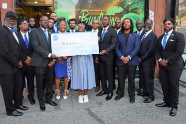 Nadege Fleurimond, center, displays check from Brooklyn Sigmas, flanked by Dr. Luc Severe's sister, Rebekah Severe, to Fleurimend's immediate right, and members of the Brooklyn Sigmas.