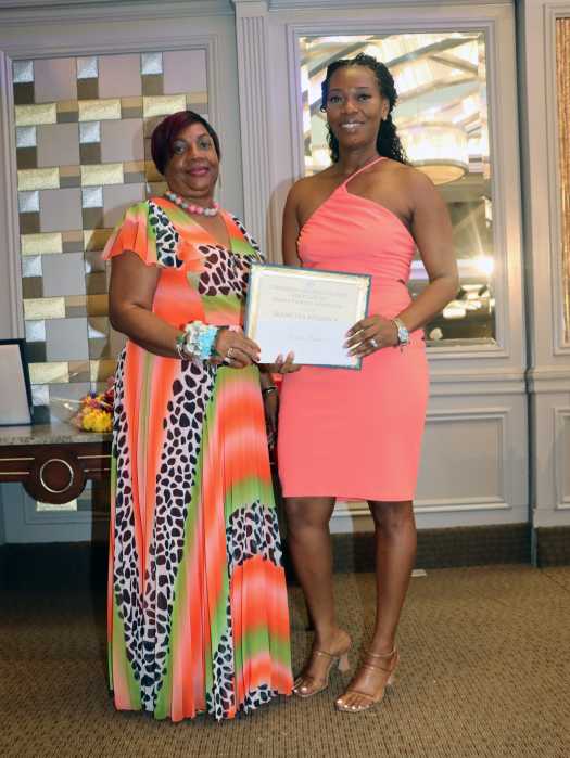 Guyanese-born Seanetta Reddock, a “dedicated and accomplished healthcare professional” with over 19 years of experience in radiologic technology and a growing career in nursing, right, receives the Monica Puckerin Scholarship Award from Dr. Cicely Wilkinson.