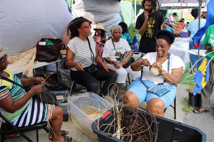 The ladies joyfully weave baskets during an instruction, as part of the afternoon of entertainment, and resource activities at an Aug. 10, Bankra Caribbean Folk Festival on the Holy Family Church tarmac in Canarsie, Brooklyn.