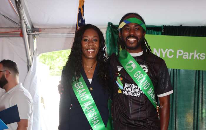 Roxaane Joseph and Atiba Edwards smile for a photo while wearing green ribbons to represent their roles as grand marshals at the Caribbean Carnival Parade.