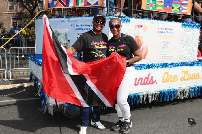 Julian John, CEO, Metropolitan Hospital, displays Trinidad and Tobago flag, with Chief-of-Staff Leticia Theodore-Greene, next to Metropolitan Hospital float