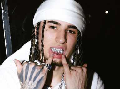 Milan-born music artist Rondodasosa shows his teeth while looking at the camera.