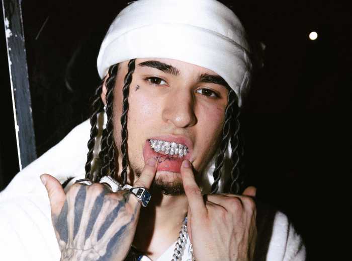 Milan-born music artist Rondodasosa shows his teeth while looking at the camera.