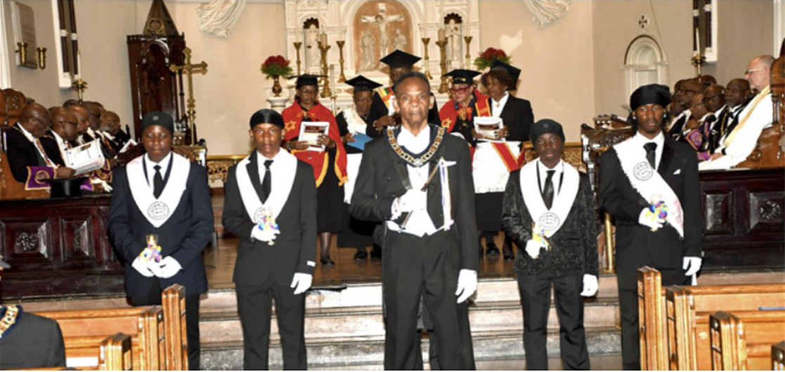 Members of the IOUM Youth Sector under the direction of Hon. Maurice Stewart (center) with members of the mechanics Choir in the background joined with the congregation in the candle ceremony, for a tribute to the 911 victims.
