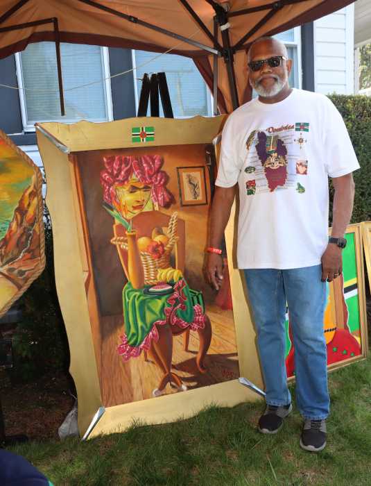 Dominican artist David G. Wilson stands besides his artwork.