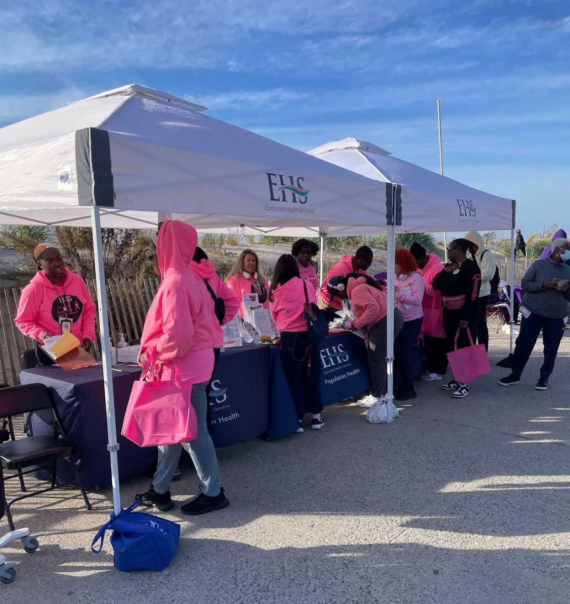 A group of attendees, at booths getting ready for the 8th Annual Trina Williams Far Rockaway Breast Cancer and Domestic Violence Awareness Walk, sponsored by various local organizations, including The Campaign Against Hunger (TCAH).