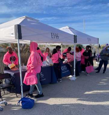 A group of attendees, at booths getting ready for the 8th Annual Trina Williams Far Rockaway Breast Cancer and Domestic Violence Awareness Walk, sponsored by various local organizations, including The Campaign Against Hunger (TCAH).