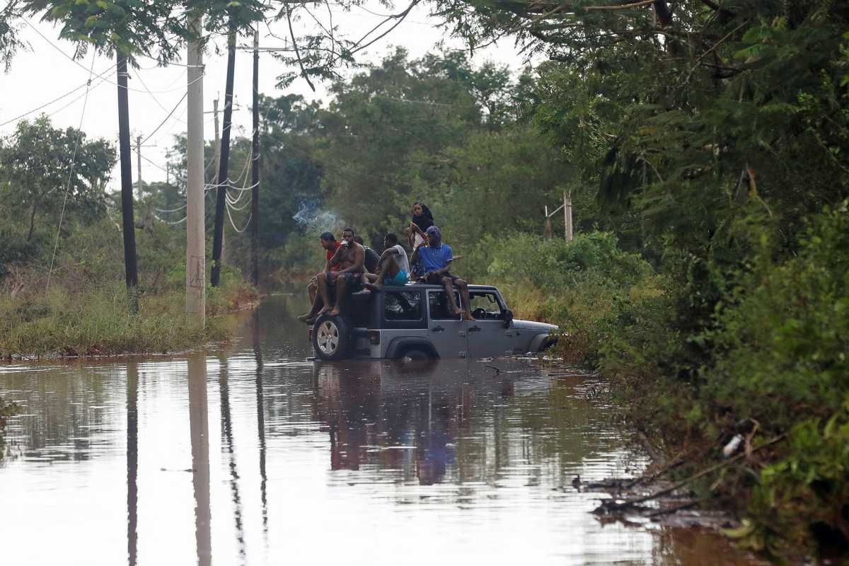 People sit on the roof of a vehicle riding on a flooded road, after Hurricane Melissa made landfall, in Prospect, Manchester, Jamaica, Oct. 29, 2025.
