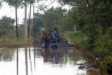 People sit on the roof of a vehicle riding on a flooded road, after Hurricane Melissa made landfall, in Prospect, Manchester, Jamaica, Oct. 29, 2025.