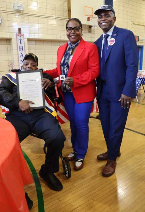 Veteran Rev. Dr. Roberts Williams, in wheel chair, displays proclamation with New York State Assembly Member Stefani L. Zinerman and NYC Department of Veterans' Services Commissioner James W. Hendon.