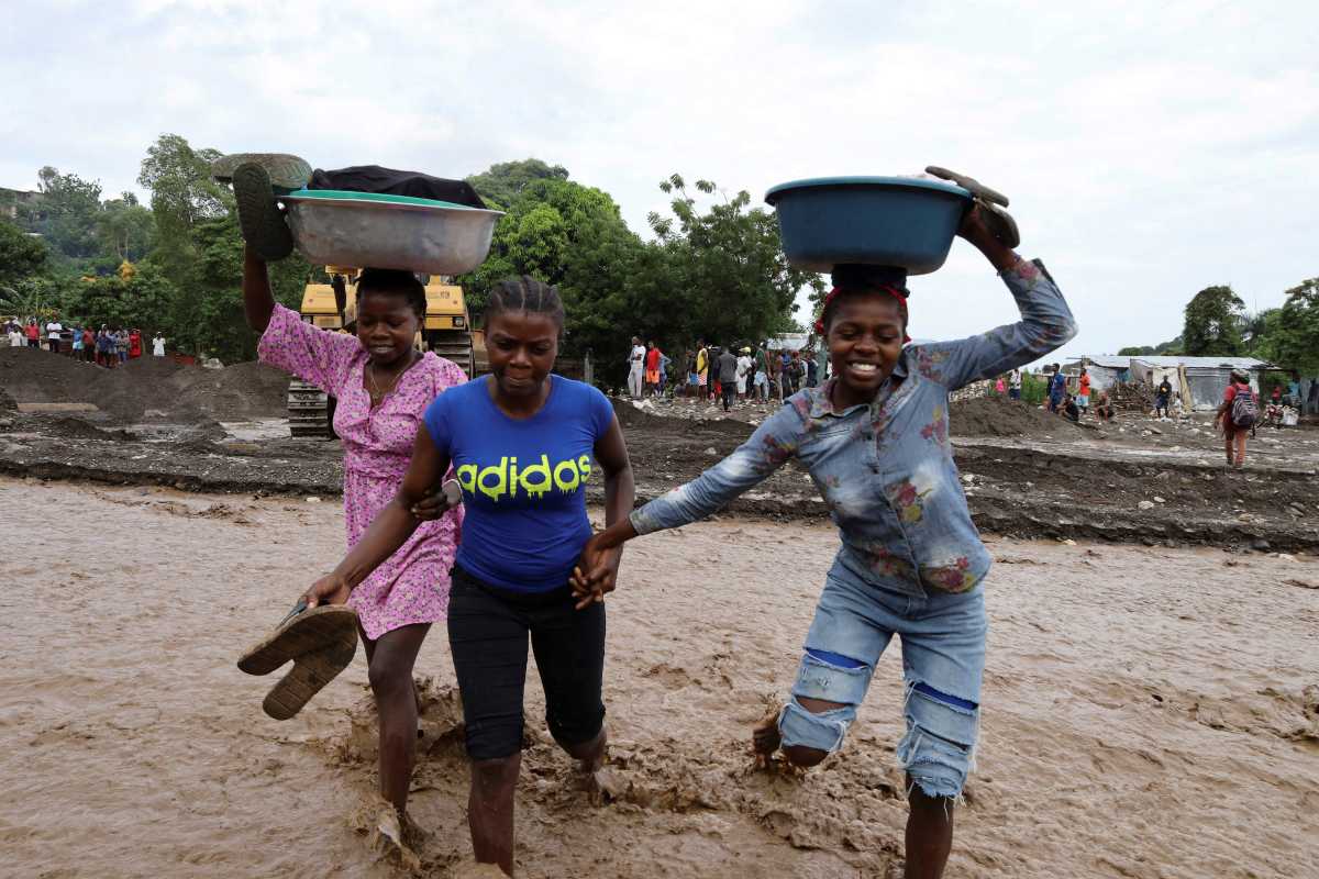 Women hold belongings as they cross a flooded area after heavy rains brought by Hurricane Melissa caused deadly flooding, in Petit Goave, Haiti October 31, 2025.